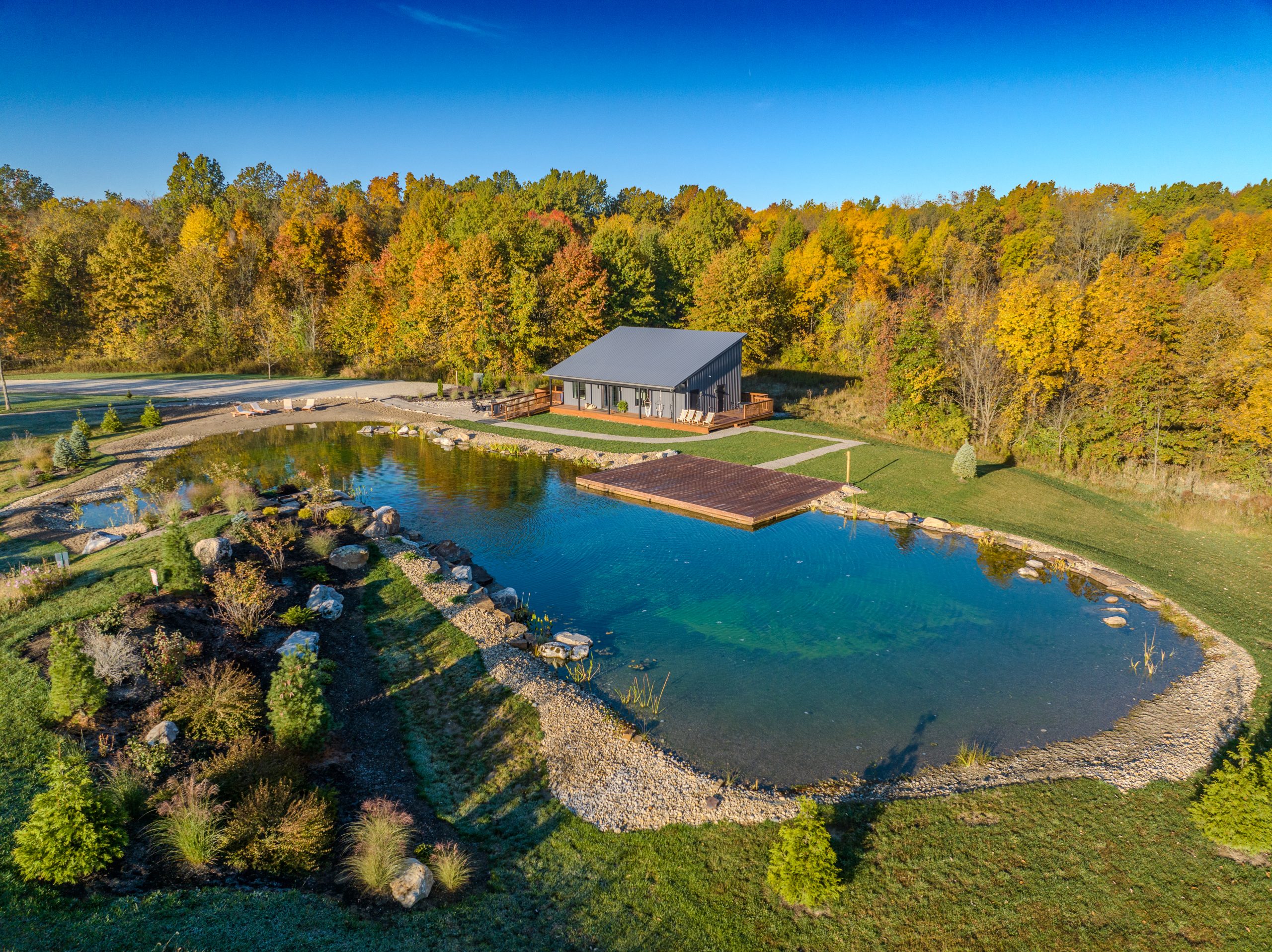 Aerial view of corporate retreat grounds at Retreat 21 during fall, featuring water, woods, and event building near Columbus, Ohio
