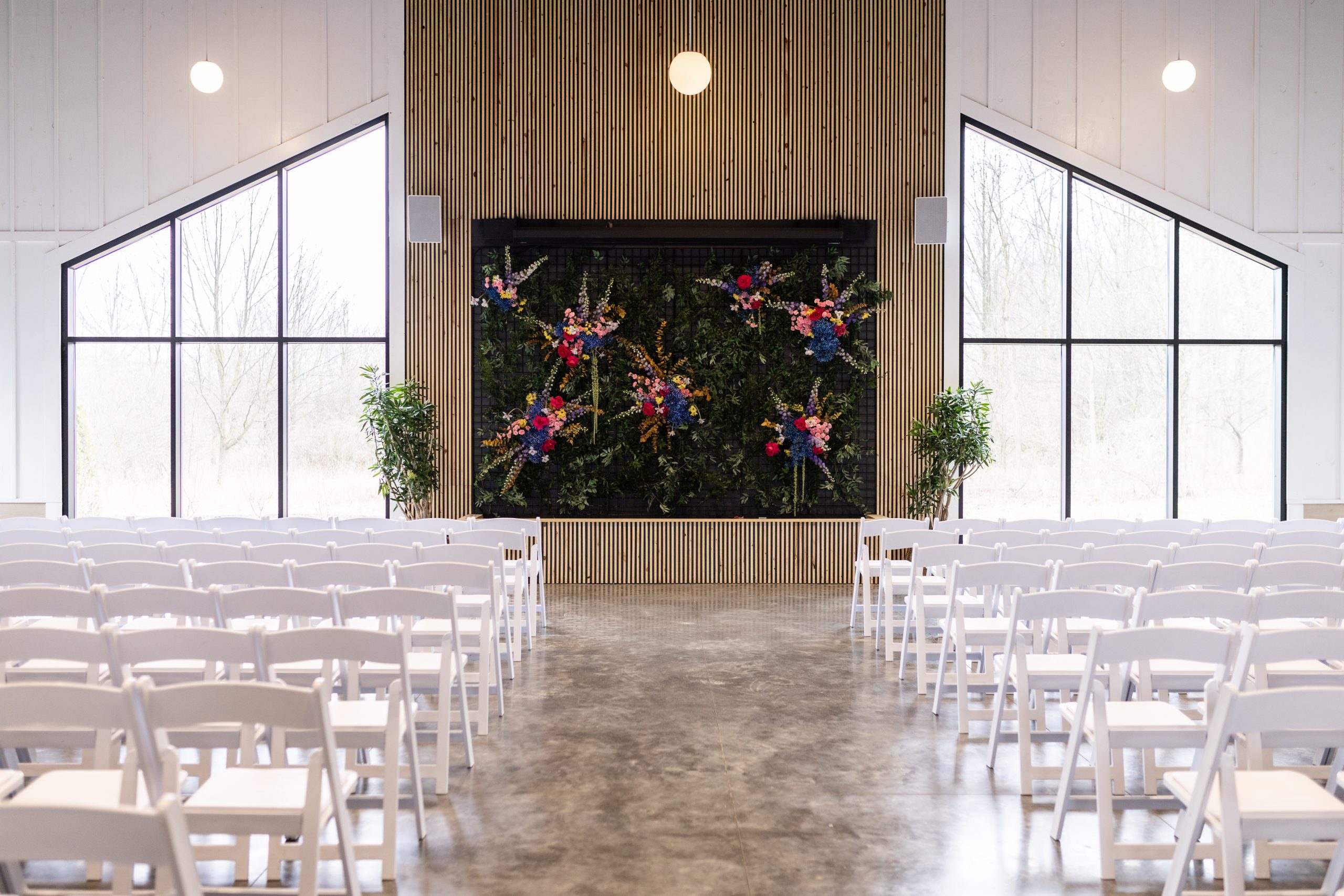 Indoor wedding ceremony setup with white chairs and large windows in an empty room at Retreat 21 near Columbus, Ohio