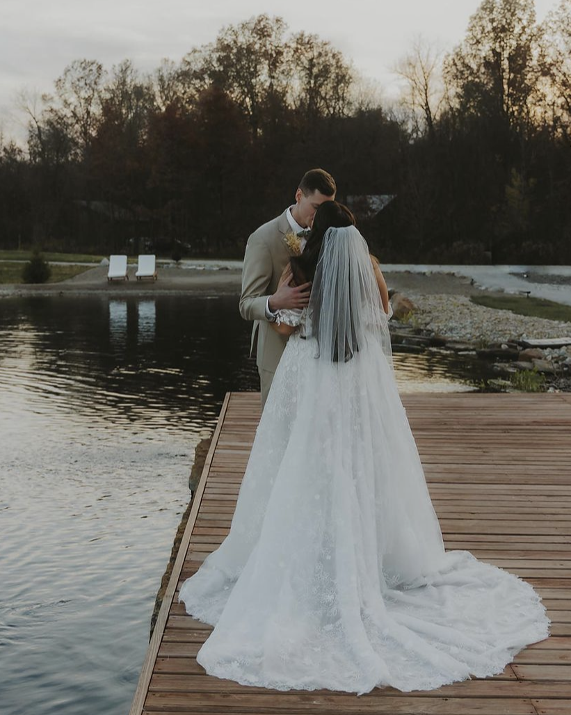 Bride and groom kiss on a dock by the water at Retreat 21, romantic outdoor wedding moment near Columbus, Ohio