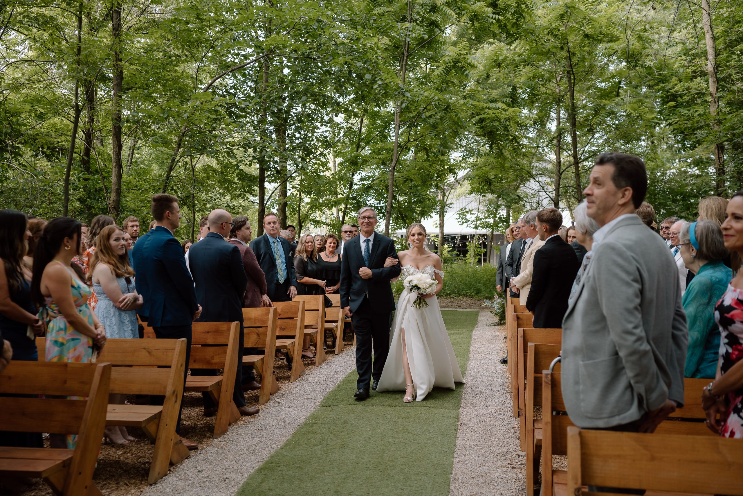 Bride walking down the aisle with her father toward outdoor ceremony space, guests standing on either side at Retreat 21 near Columbus, Ohio