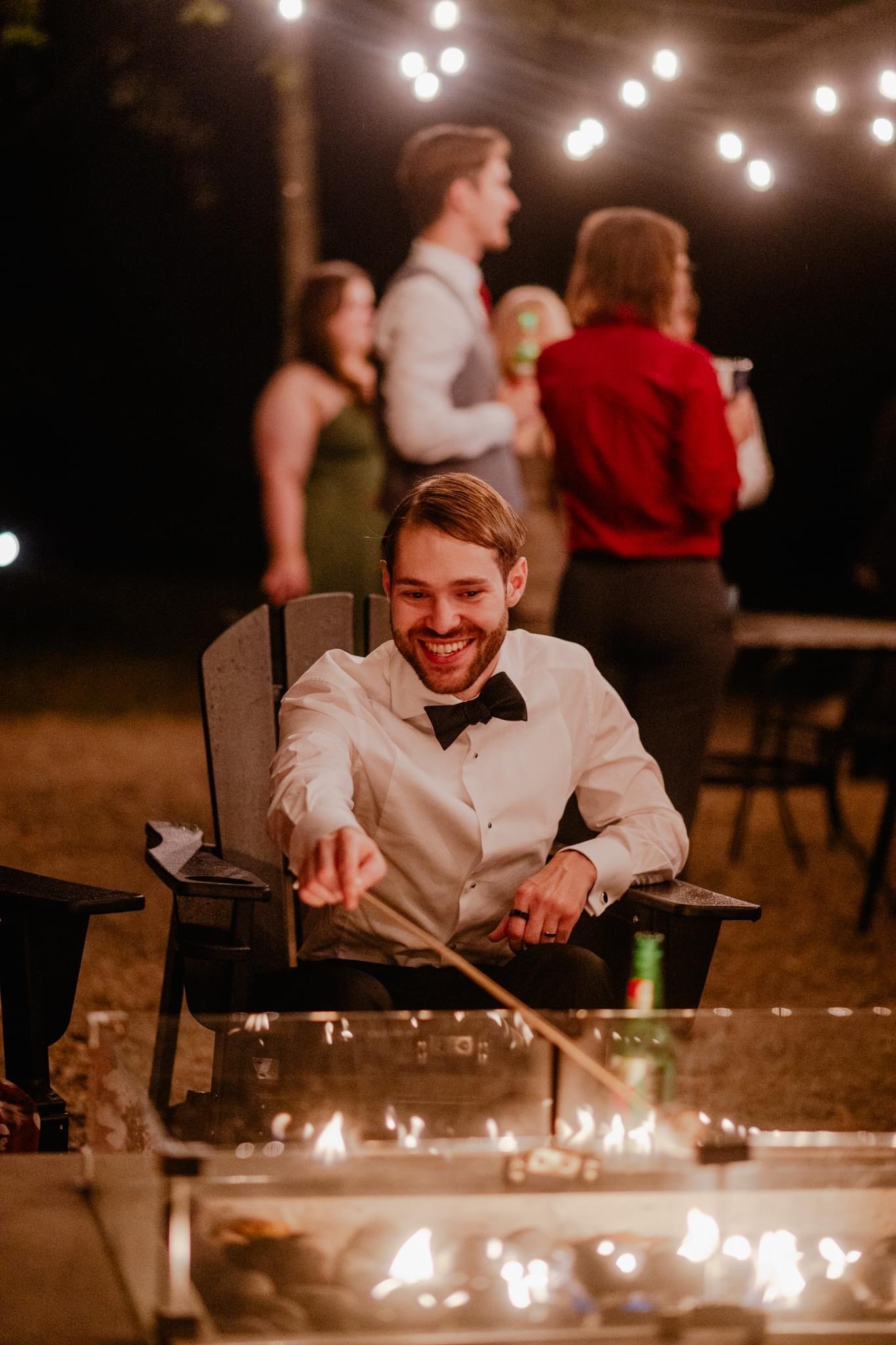 Man in tuxedo smiling outdoors at night with string lights and fireplace at Retreat 21 near Columbus, Ohio