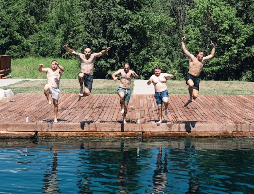 Group of men jumping into the water together during a wedding weekend at Retreat 21 near Columbus, Ohio
