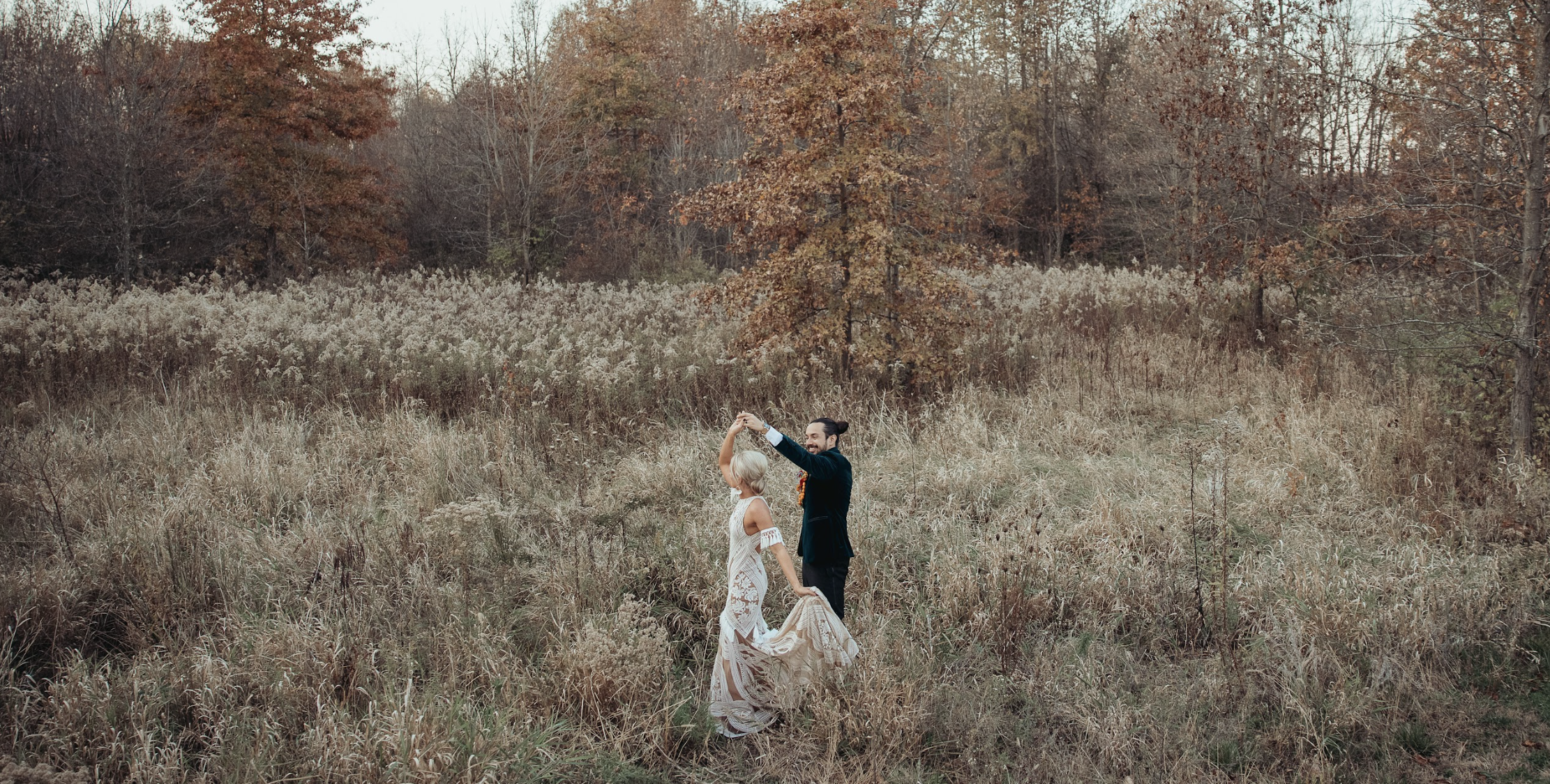 Bride and groom standing in a field with fall foliage in the background at Retreat 21 near Columbus, Ohio