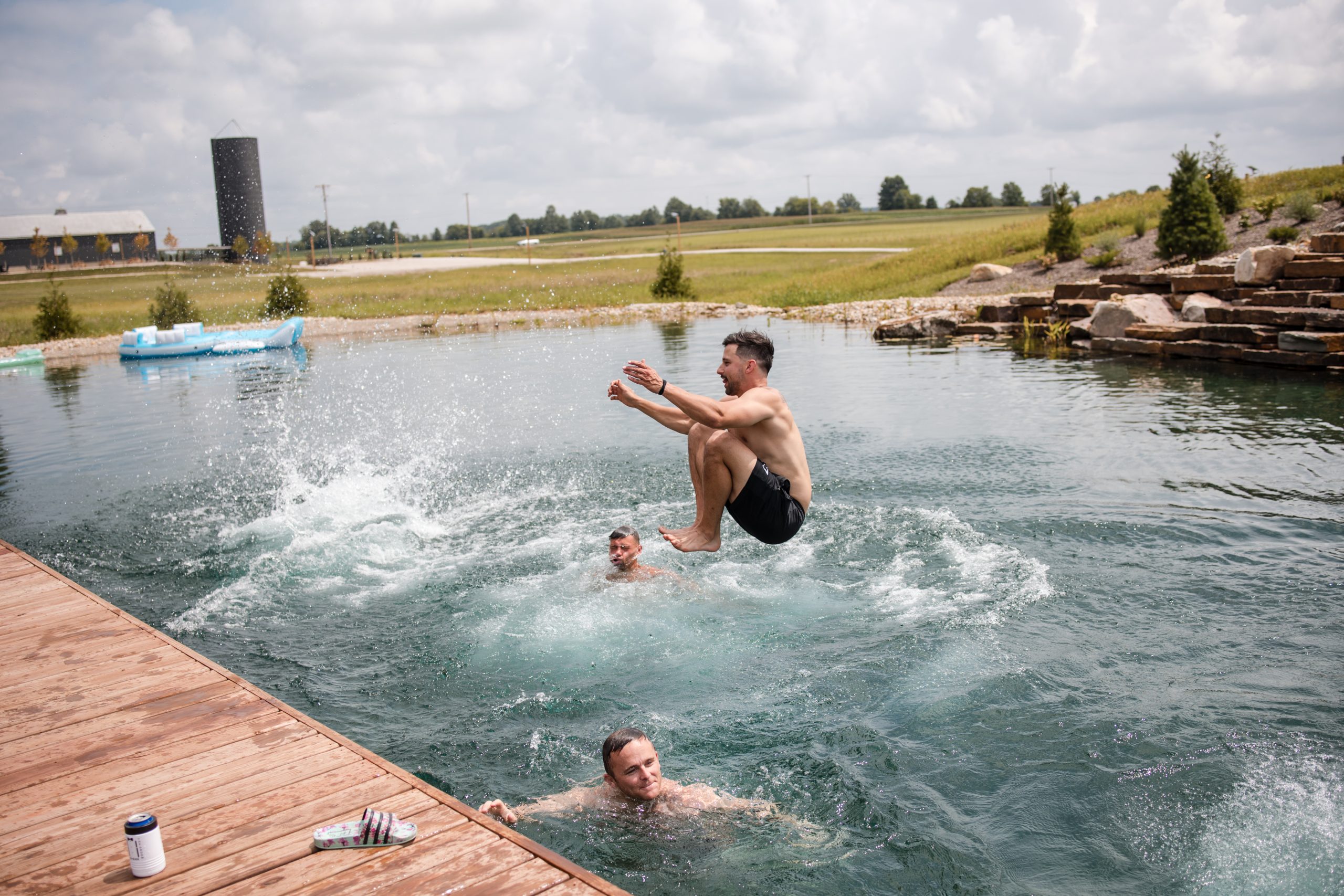 Man jumping into the water while others swim during a wedding weekend at Retreat 21 near Columbus, Ohio