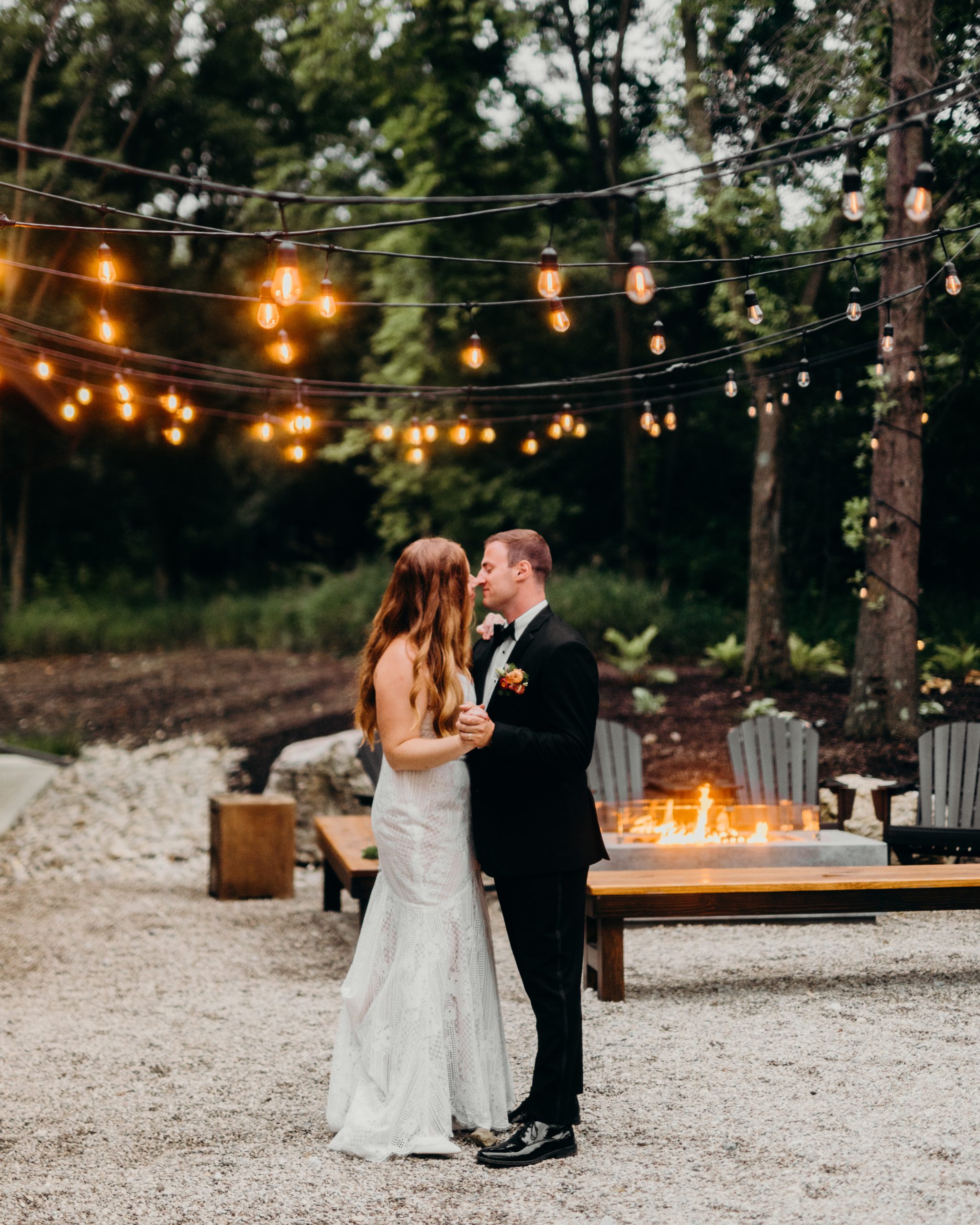 Bride and groom dancing alone outdoors under string lights with a fire in the background at Retreat 21 near Columbus, Ohio