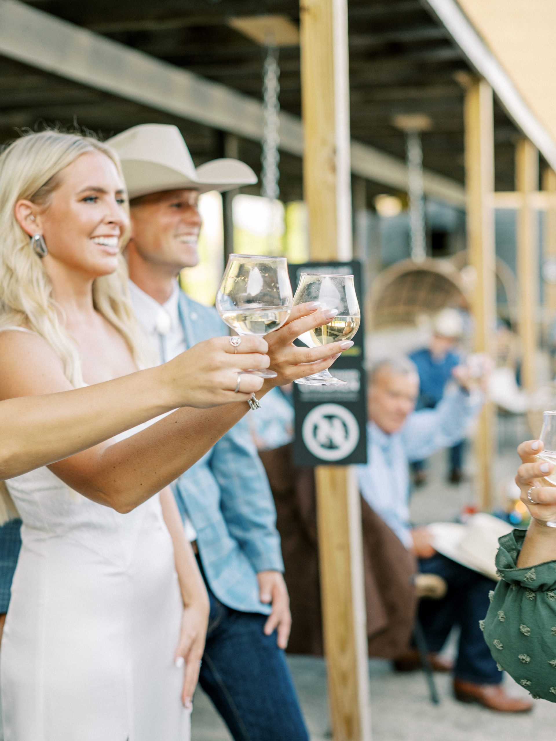 sierradyerco-burns-wedding-rehearsal-124 Bride and groom, with groom in cowboy hat, raising a toast to guests at Retreat 21 near Columbus, Ohio