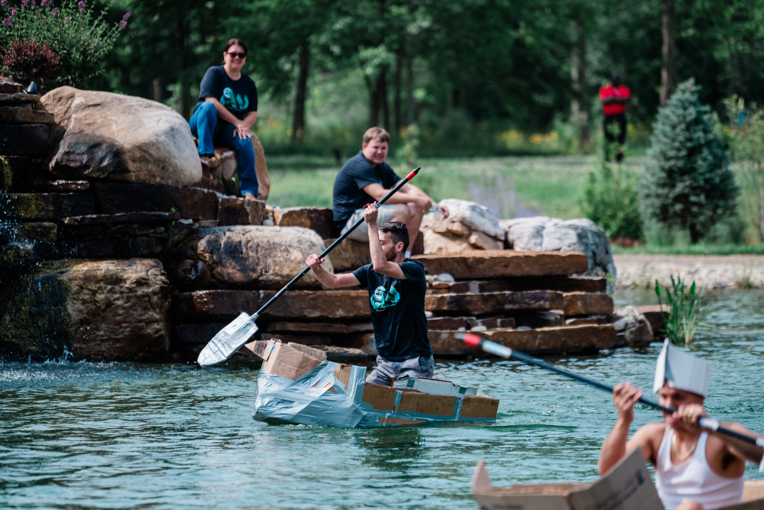 A corporate team participating in a collaborative outdoor activity in the natural swimming pond at Retreat 21 in Marysville, Ohio.