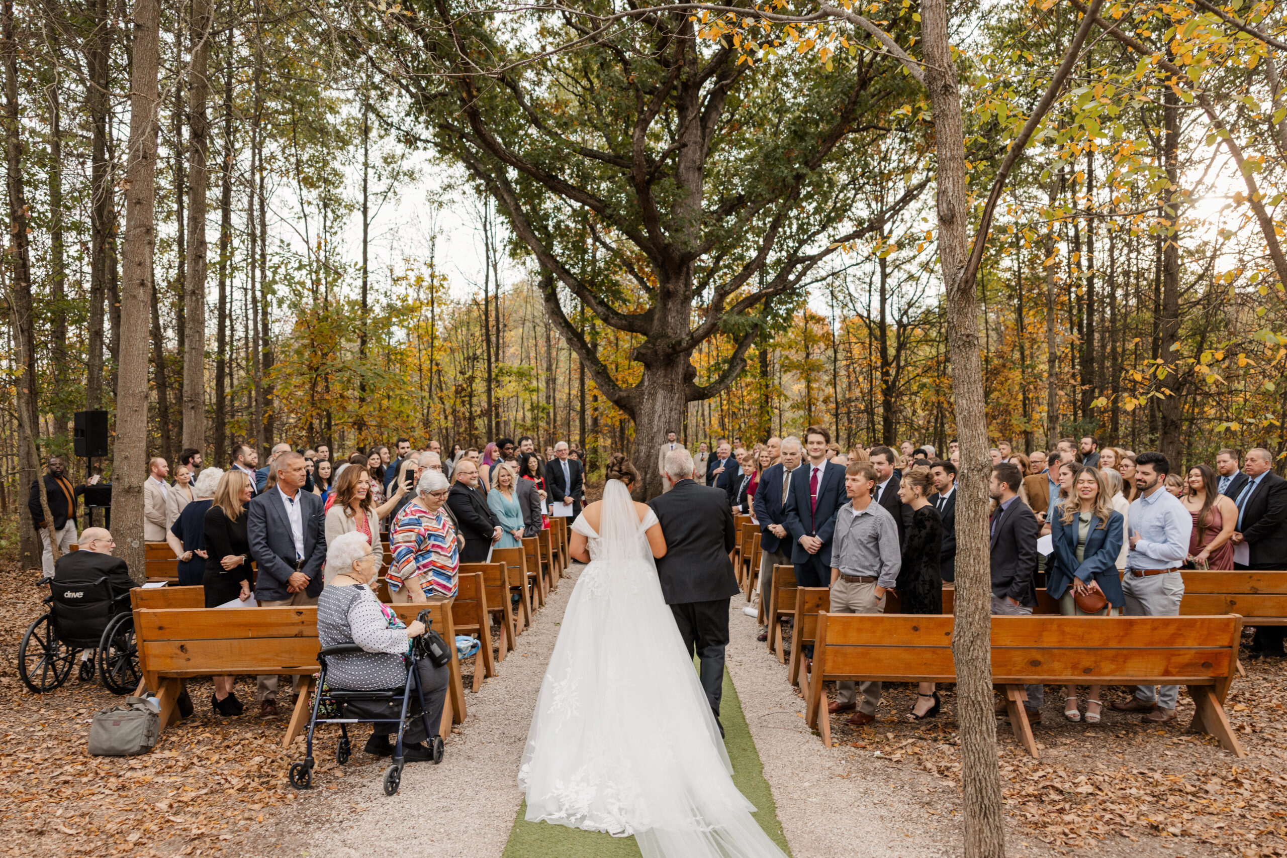 J+J-99 Bride walking down the aisle with her father toward outdoor ceremony space, guests standing on either side at Retreat 21 near Columbus, Ohio