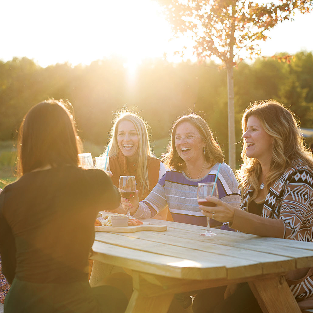 Ladies toasting with glasses of wine and cider at the Taphouse on the outdoor patio.